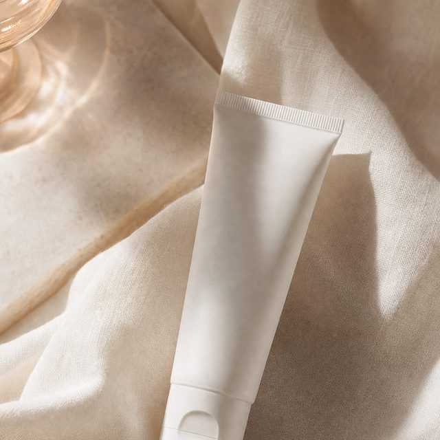 Minimal white gel tube resting on ivory linen in soft window light